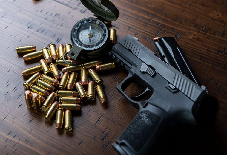 A semi-automatic pistol beside loose brass handgun cartridges